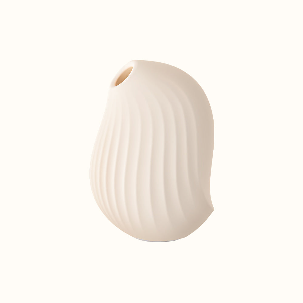 A compact, cream, ergonomic clitoral sucking device designed for pleasure, with a smooth surface and body safe silicone