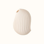 A compact, cream, ergonomic clitoral sucking device designed for pleasure, with a smooth surface and body safe silicone
