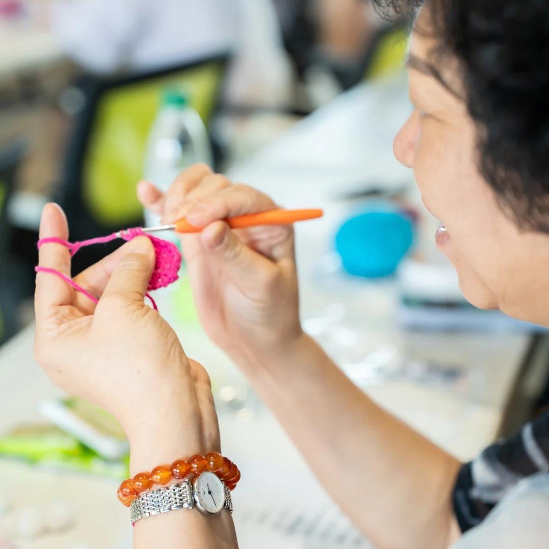 A older women is crocheting the pink vulva keychain 