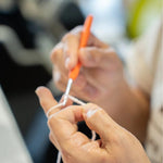 A woman is hand-knitting a clitoris keychain.