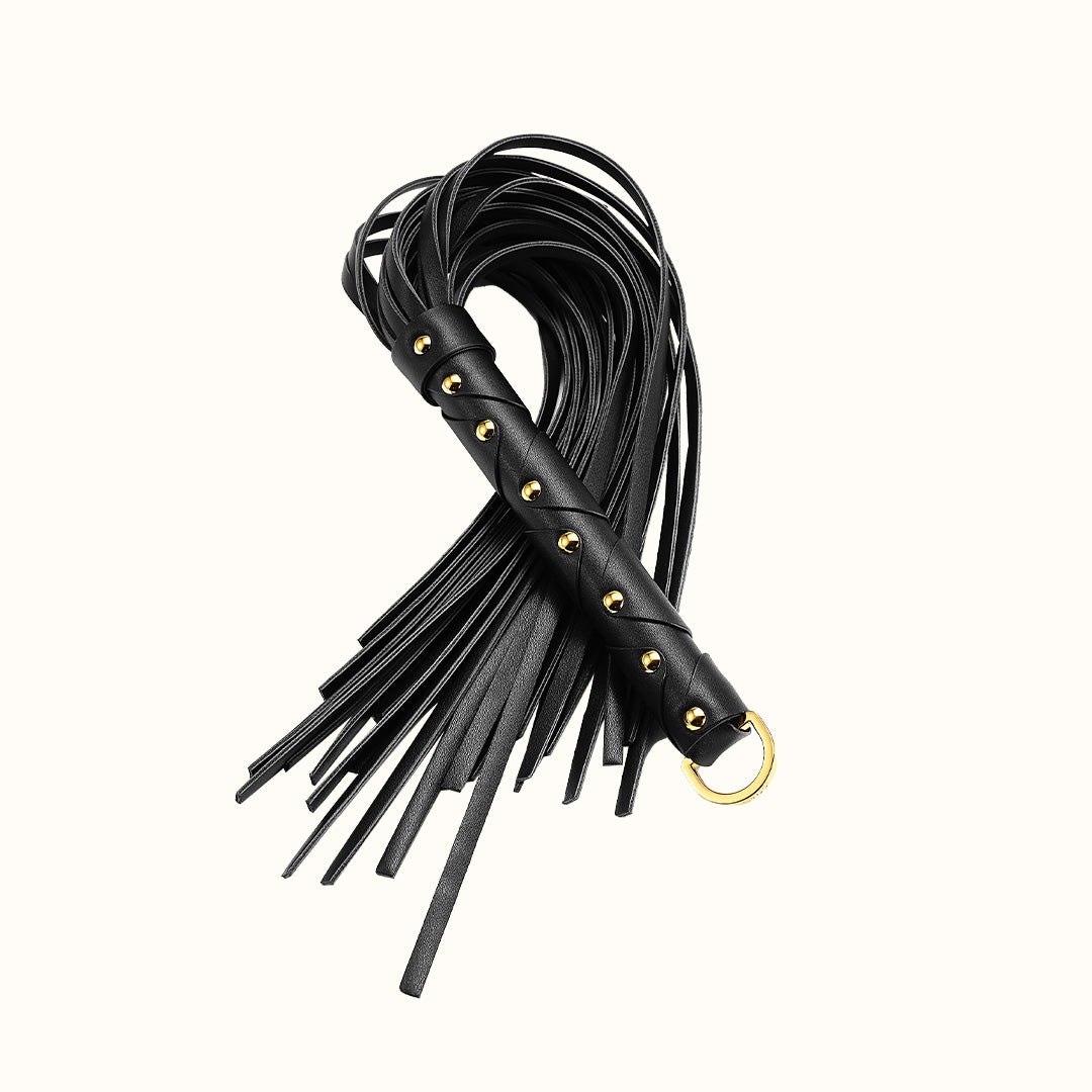 Black leather whip with gold accents and hanging loop