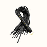 Black leather whip with gold accents and hanging loop